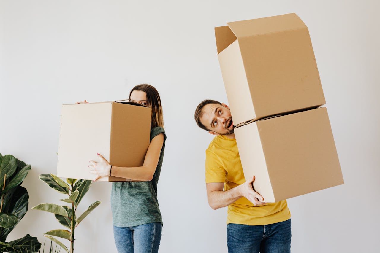 A happy couple carrying boxes while moving into their new home.