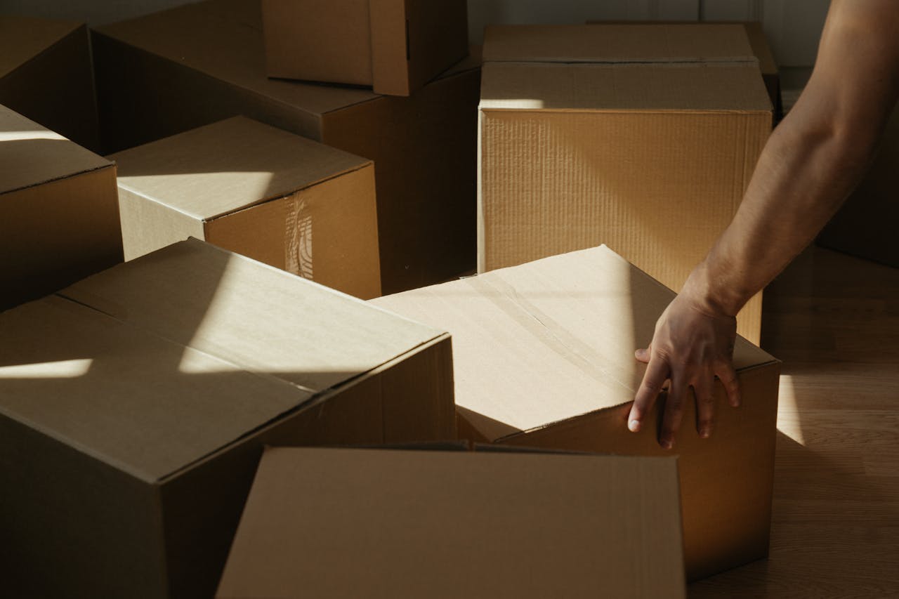 Sunlit room with person moving cardboard boxes, symbolizing relocation and new beginnings.